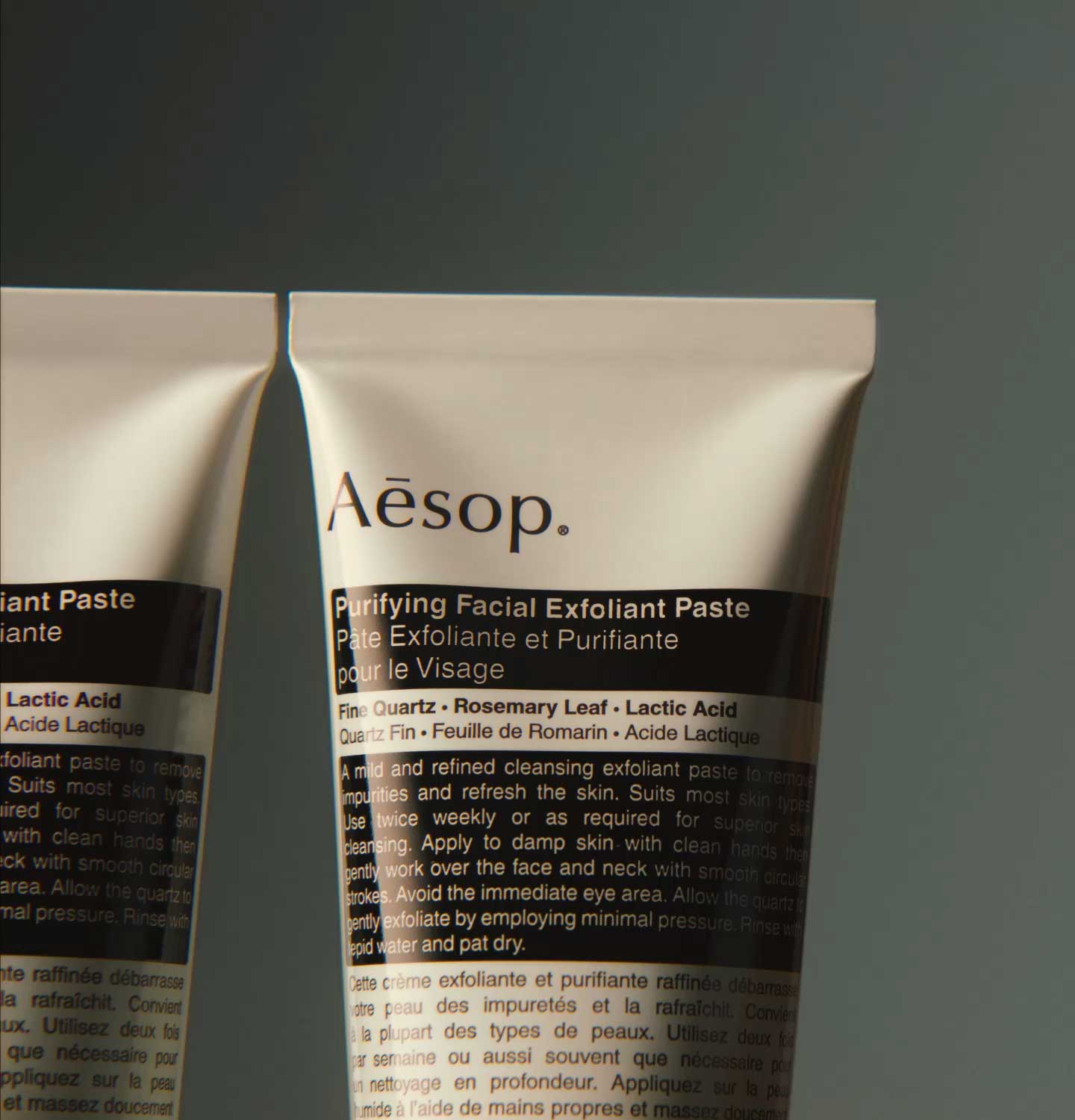 Purifying Facial Exfoliant Paste in aluminium tube placed in front of textured teal background