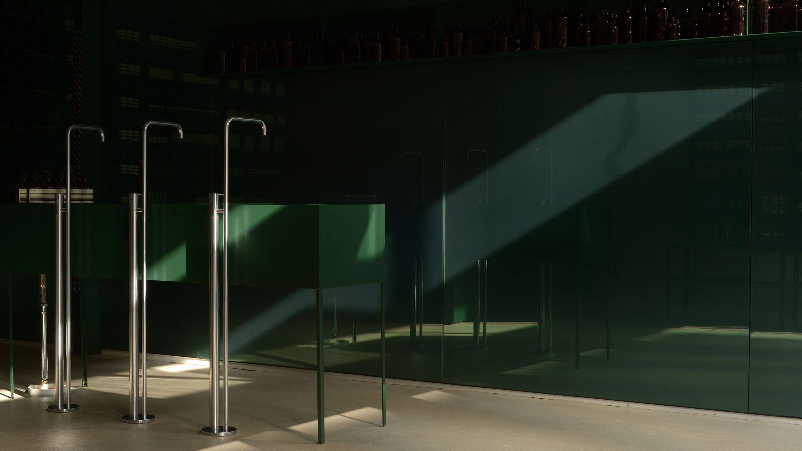 Light rays falling across the wall and central basin of an Aesop store.