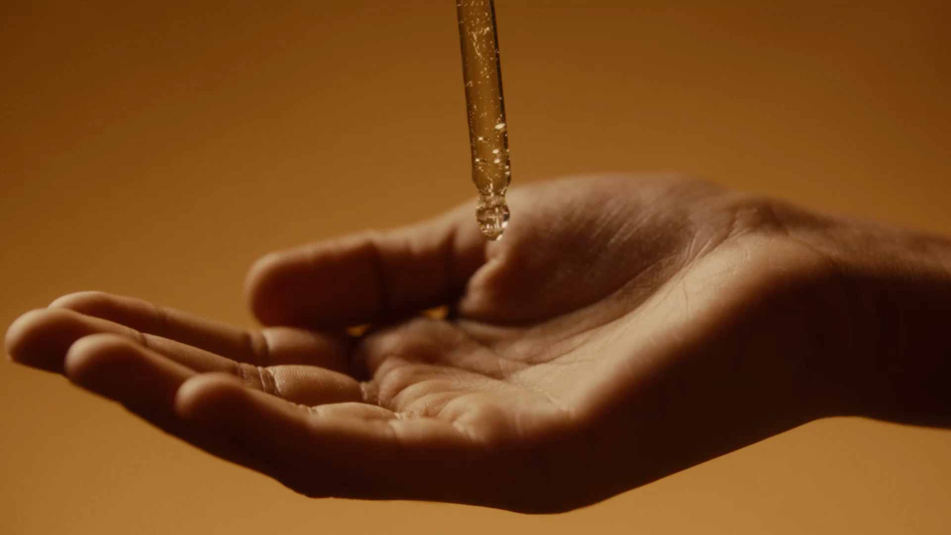A clear, lightweight serum streams from the pipette into the bottle.