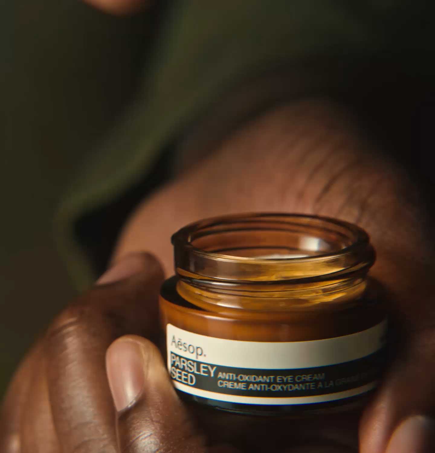 Hand holding a Parsley Seed Anti-Oxidant Eye Cream jar