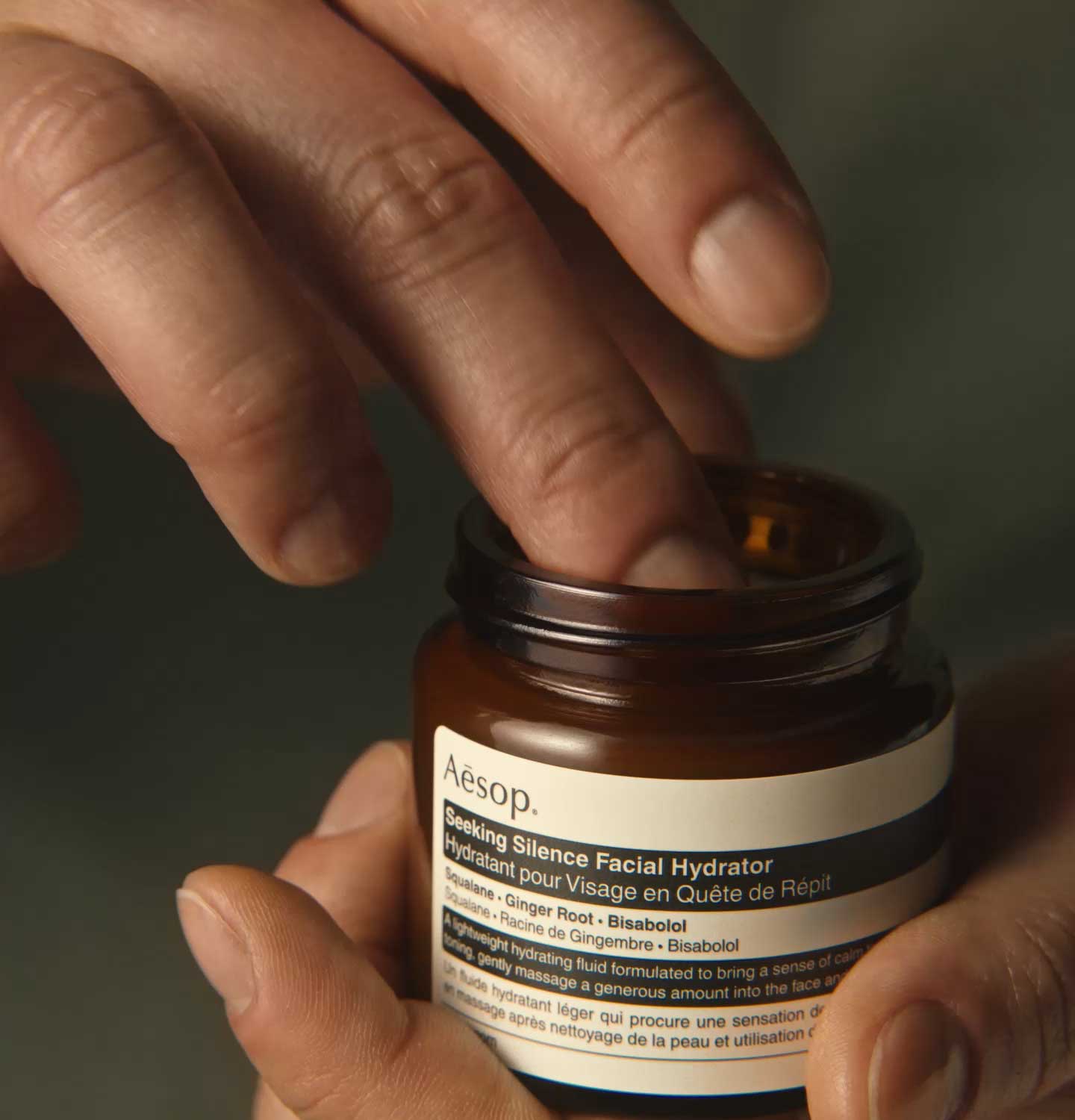 A hand dipping fingers in an amber glass jar