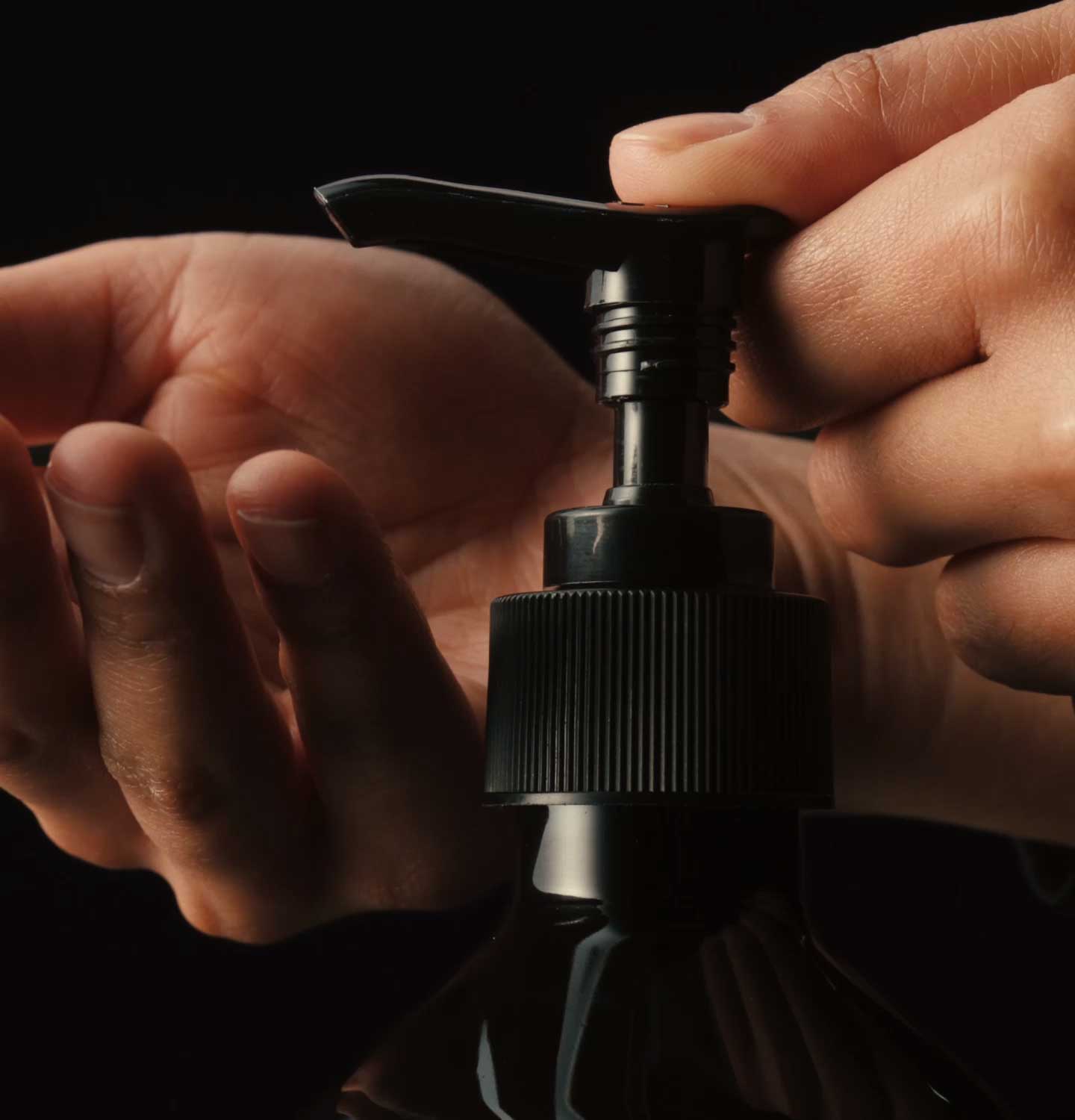 Hands dispensing product from amber bottle with pump