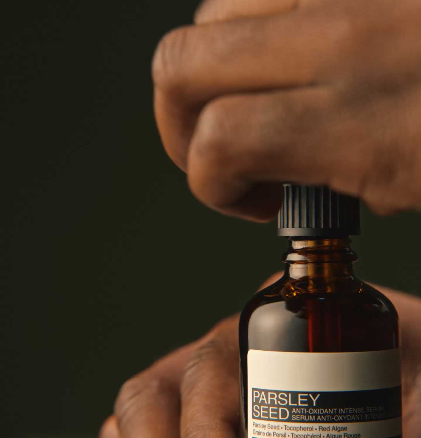 Hands opening the Parsley Seed Anti-Oxidant Intense Serum bottle