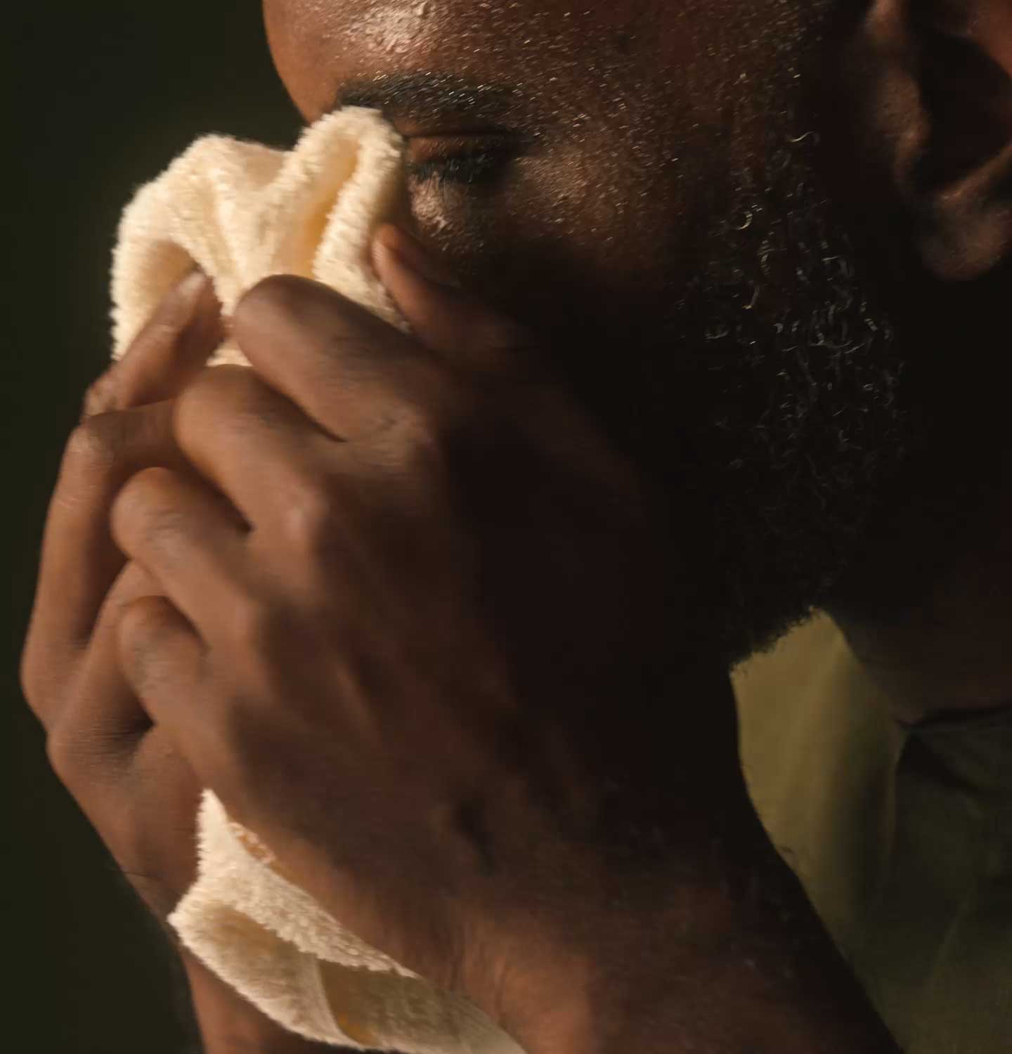 An individual holding a facial towel near the face