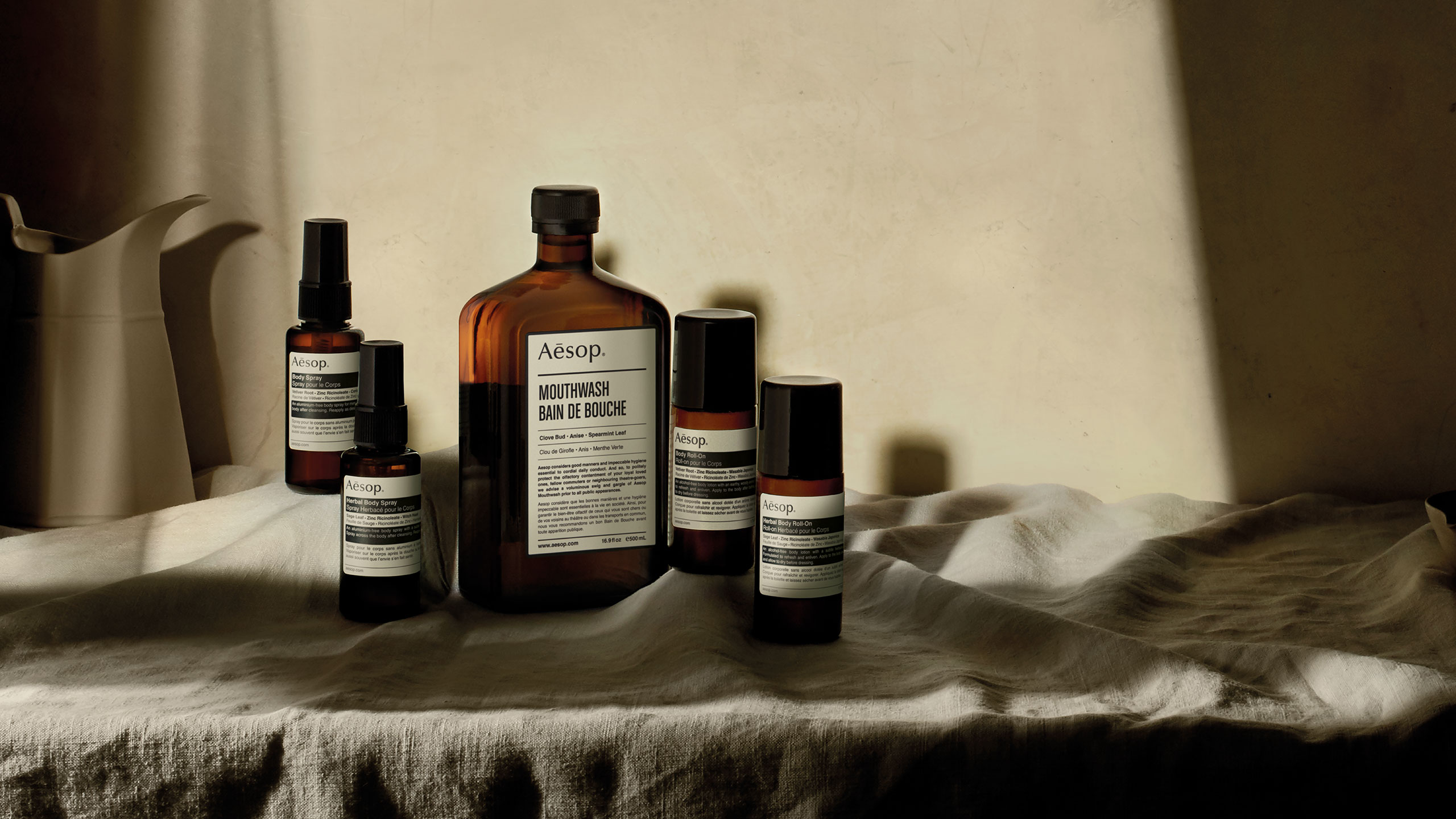 Aesop products arranged on a tablecloth, sitting in a shaft of light.